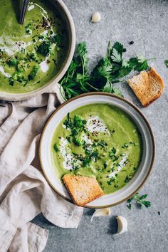 two bowls filled with green soup on top of a table