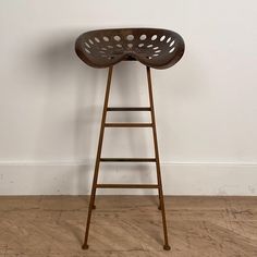 a wooden stool sitting on top of a hard wood floor next to a white wall