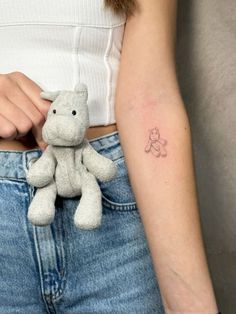 a woman with a small tattoo on her arm holding a stuffed animal in her pocket