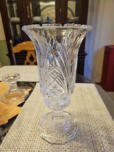 a clear glass vase sitting on top of a table next to two empty wine glasses