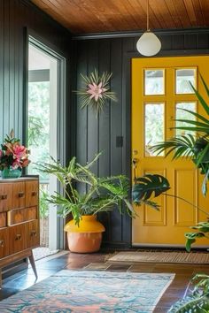 a yellow door in a room with plants on the floor and rugs around it