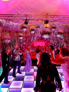 people are dancing on the dance floor in front of disco balls and chandeliers