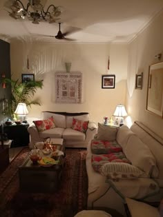 a living room with couches, lamps and pictures on the wall in it's corner