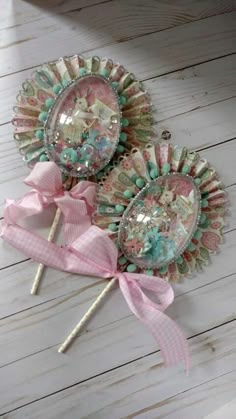 two lollipops with bows on them sitting next to each other in front of a white wooden background