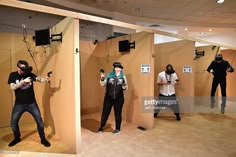 several people are playing video games in a room with cardboard walls and wires hanging from the ceiling