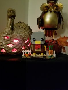 a figurine that is sitting on a table next to a turkey and some pumpkins