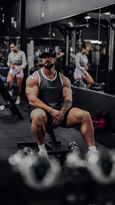 a man sitting on top of a bench in front of a gym equipment line with other men