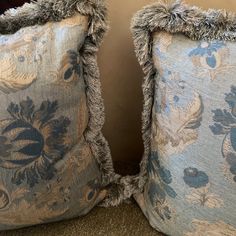 two decorative pillows are sitting on the floor next to each other, both with fringed edges