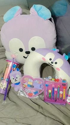 stuffed animals and toys on a bed with pillows, pencils, pens and other items