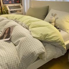 an unmade bed in a bedroom next to a window with curtains and pillows on it