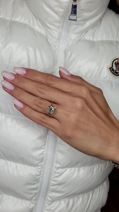 a woman's hand with a ring on her finger and a white puffy coat