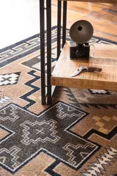 a coffee table sitting on top of a rug in front of a wooden table with a lamp