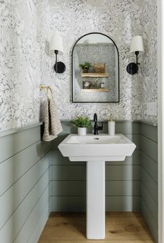 a white sink sitting under a bathroom mirror next to a wall mounted faucet