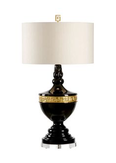 a black and gold table lamp with a white shade on the top, in front of a white background