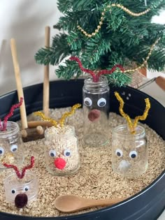 some glass jars filled with sand and fake reindeer noses are sitting in front of a christmas tree