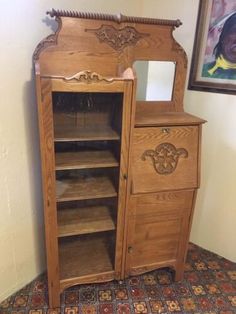 an old fashioned wooden cabinet with mirror on it's door and shelves in the corner