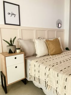 a bedroom with a bed, nightstand and plant on the side table in front of it