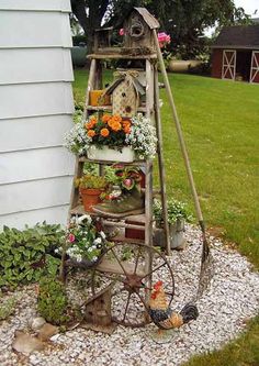 an old fashioned garden stand with flowers and chickens on it in front of a house