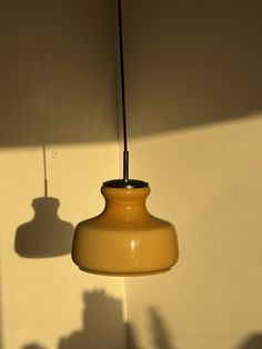 a yellow light hanging from a ceiling next to a wall with shadows on the wall