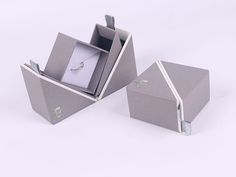 an open box with a ring inside on a white surface, next to another one