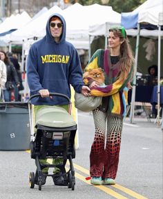 a man and woman walking down the street with a stroller