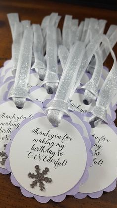 some white and purple tags with silver snowflakes on them sitting on a table