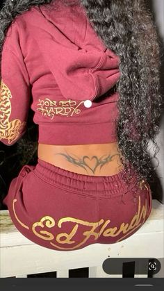 the back of a woman's red sweatsuit with gold lettering on it, and her hair is curled up