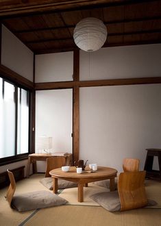 an empty room with two chairs and a round table in the middle, next to large windows