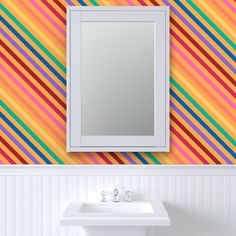 a bathroom sink sitting under a mirror next to a wall mounted faucet in front of a colorful striped wall