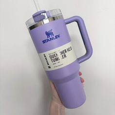 a person holding up a purple travel mug