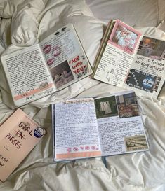 an open book sitting on top of a bed next to two other books and papers