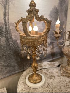 an ornate candle holder with three lit candles on top of a marble table in front of a wallpapered background