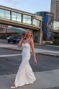 a woman in a white dress crossing the street