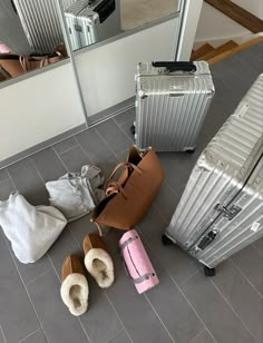 three pieces of luggage sitting on the floor in front of a mirror and two pairs of slippers