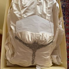 the back of a white wedding dress in a box with its hood up and belt down