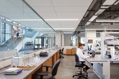 a woman working in a lab with lots of glassware on the desk and shelves