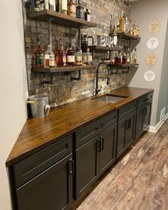 a kitchen with wooden counter tops and shelves filled with liquor bottles on the wall behind it