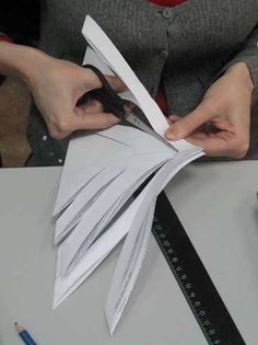 a person cutting paper with scissors on top of a table