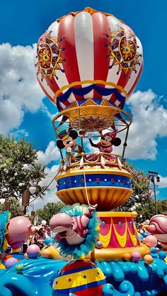 an amusement park float with mickey and minnie mouses on it's top, in the air