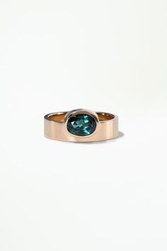 a gold ring with a green stone in the center on a white background, it is also part of a jewelry collection