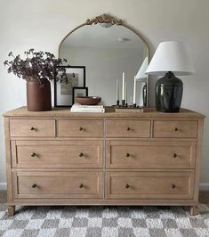 a wooden dresser with many drawers and vases on top of it in front of a mirror