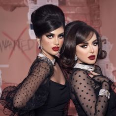 two beautiful women in black dresses posing for a photo with red lipstick on their faces