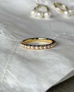 two gold wedding bands with white pearls on the bottom, and one in yellow gold