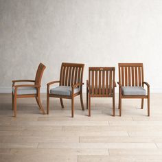 three wooden chairs sitting next to each other on top of a hard wood floor in front of a white wall