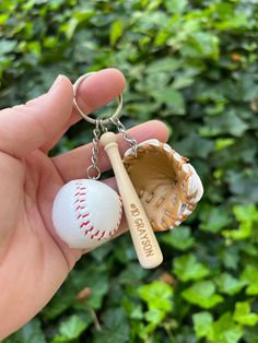 a hand holding a baseball and bat shaped keychain