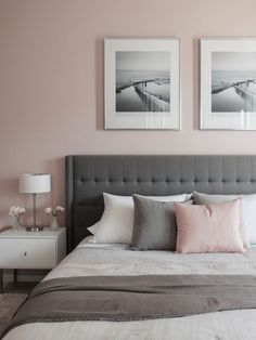 a bedroom with pink walls and two pictures on the wall above the bed in front of it