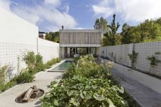 a house with a pool in the middle surrounded by greenery and trees on both sides