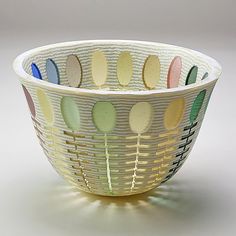 a white bowl filled with lots of different colored spoons on top of a table