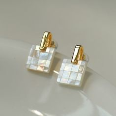 Introducing our elegant patchwork white mother-of-pearl checkerboard earrings, a perfect blend of style and craftsmanship. Each earring is carefully pieced together from white mother-of-pearl in a charming checkerboard pattern, creating a striking visual contrast. Mother-of-pearl exudes timeless elegance, while the checkerboard design adds a contemporary edge. These earrings are lightweight and comfortable to wear. Metal: 18K Recycled Gold Plated On Brass Gemstone: Mother of Pearls Earrings Dime Luxury Handmade Mother Of Pearl Jewelry, Handmade White Earrings In Mother Of Pearl, Handmade White Mother Of Pearl Earrings, Rectangular White Jewelry With Pearl Drop, White Mother Of Pearl Jewelry With Buttons, Square White Earrings For Gift, Inlaid Jewelry, Edison Pearls, White Studs