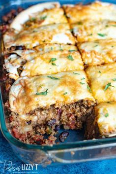 a casserole dish with meat and cheese in it on a blue tablecloth